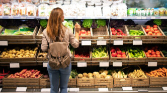 Chica joven comprando en una tienda de frutas y verduras