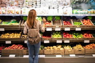 Chica joven comprando en una tienda de frutas y verduras
