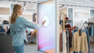 Chica interactuando con una pantalla digital en una tienda física de ropa