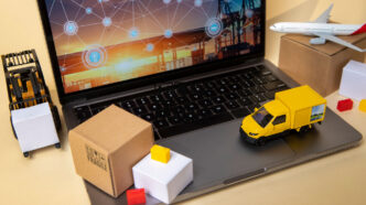 Un camión, un avión y cajas en miniatura sobre un portátil para simbolizar el cash&carry