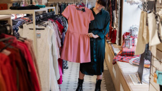 Chica en una tienda de ropa mirando un vestido