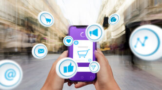 Unas manos sujetan un móvil del que salen iconos relacionados con el retail media
