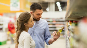 Una pareja revisando la etiqueta de un producto en un supermercado antes de comprarlo