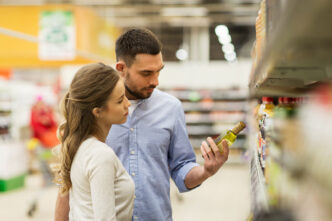 Una pareja revisando la etiqueta de un producto en un supermercado antes de comprarlo