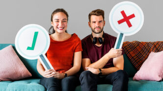 Chica y chico sentados en un sofá con signos de aprobación y desaprobación