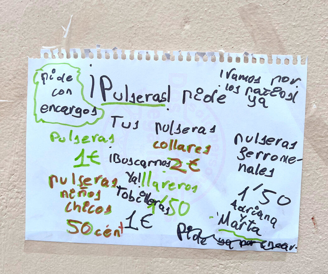 Cartel para la venta de pulseras y collares realizado por niñas en un patio vecinal