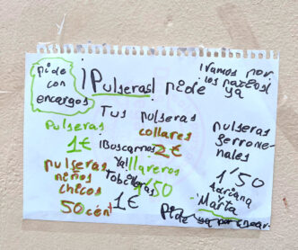 Cartel para la venta de pulseras y collares realizado por niñas en un patio vecinal